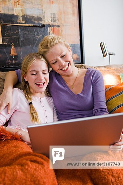 Mutter und Tochter mit einem Laptop in eine Couch  Schweden.