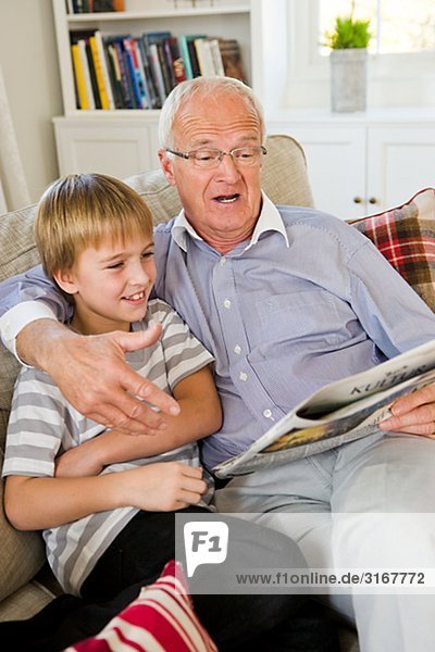 Grandfather and grandson in a sofa  reading  Sweden.