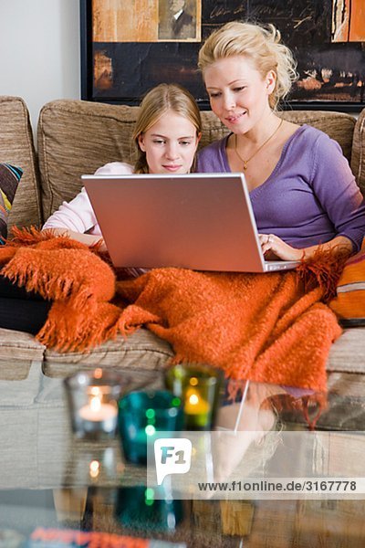 Mutter und Tochter mit einem Laptop in eine Couch  Schweden.