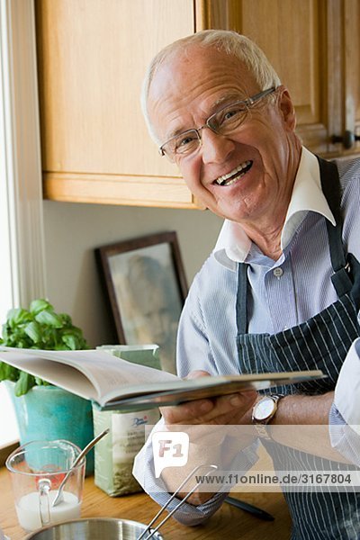älterer Mann dabei  Kochen  lesen ein Kochbuch  Schweden.