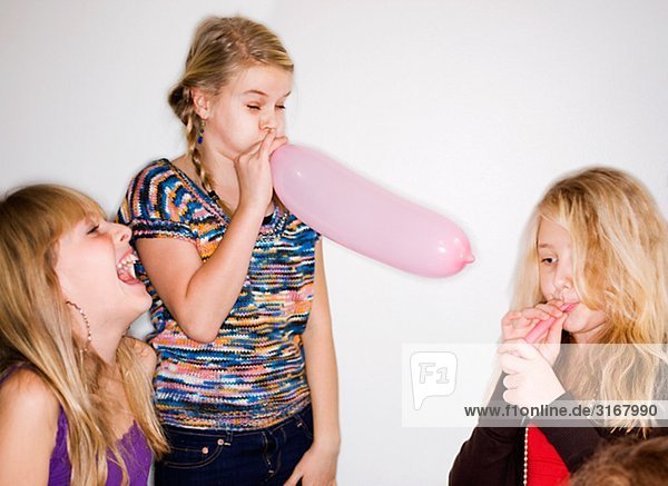 Three girls blowing up balloons  Sweden.