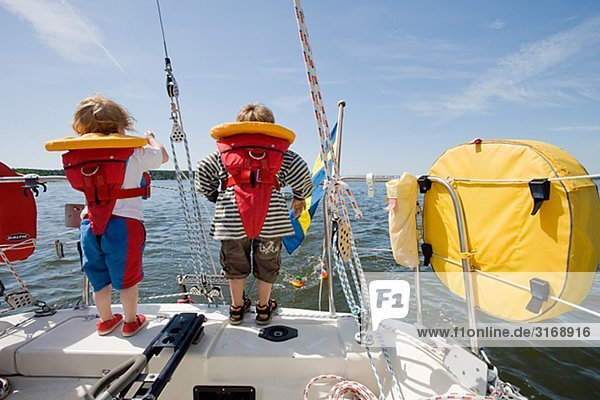 Ein Mädchen und ein Junge stehend auf einem Segelboot Schweden.