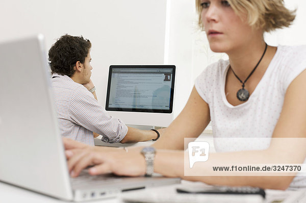Two teenager using laptop and desktop computer  horizontal format