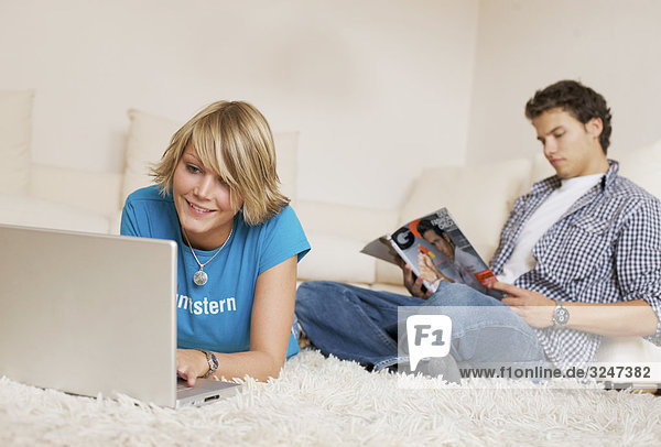 Teenager couple using media in living room  slanted view