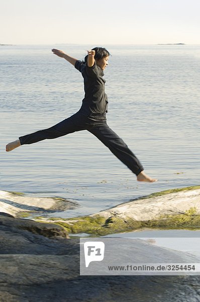 Junge Frau springen auf den Felsen am Meer  Schweden.