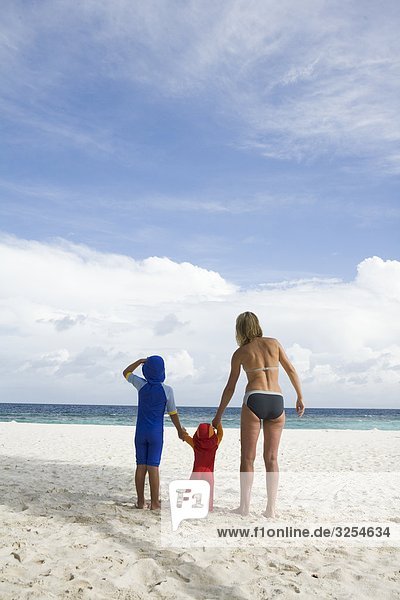 Mother walking on a beach with her two children  the Maldives.