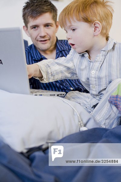 Ein Vater und sein Sohn mit einem Laptop im Zimmer  Schweden.