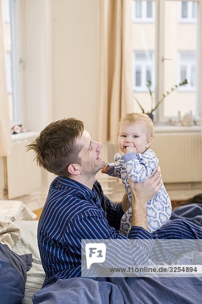 Father with his baby daughter in a bed  Sweden.