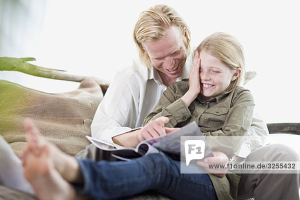 Vater und Tochter beim Lesen einer Zeitschrift