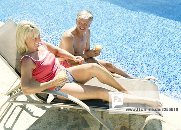 A senior couple talking by the pool