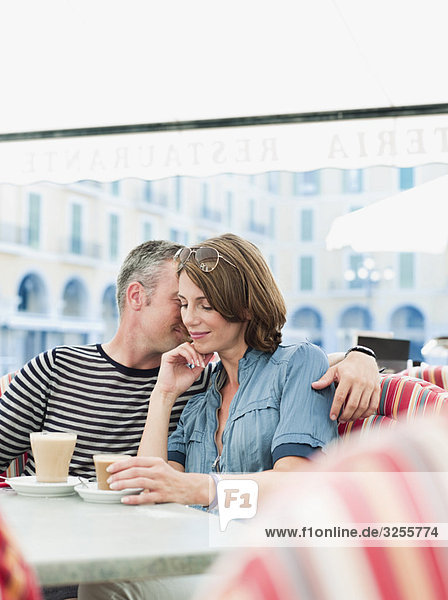 couple sitting in a city cafe smiling