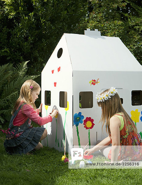 Mädchen  die ein Haus aus Pappe malen.