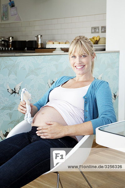 Eine schwangere Mutter hält ein Babyspielzeug.