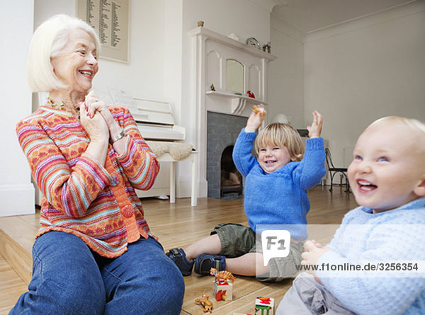 Eine Großmutter  die mit zwei Kleinkindern spielt.