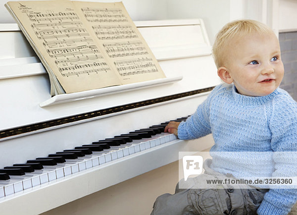 A boy toddler sitting at the piano