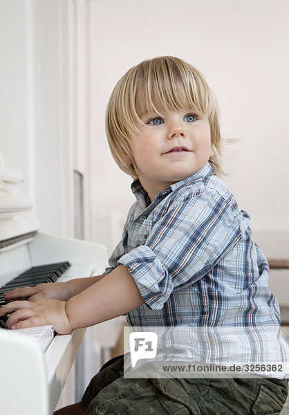 A boy toddler sitting at a piano
