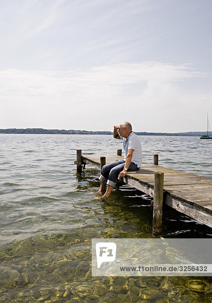 senior man sitting on pier at lake