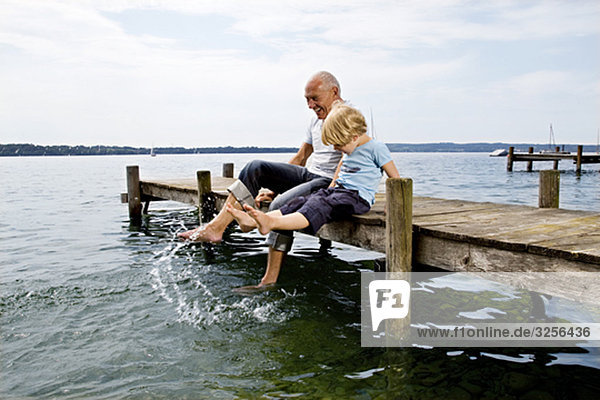 boy splashing with grandfather at lake