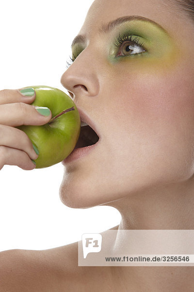 Frau beißt in den grünen Apfel
