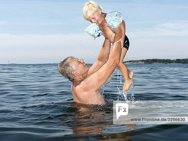 Großvater und Junge spielen im Wasser