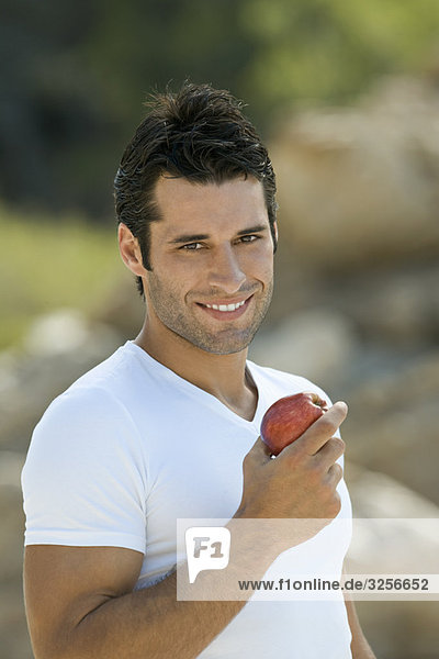 Ein lateinamerikanischer Mann mit einem lächelnden Apfel