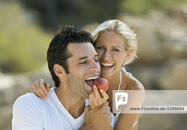 A female feeding a latin man a nectarine
