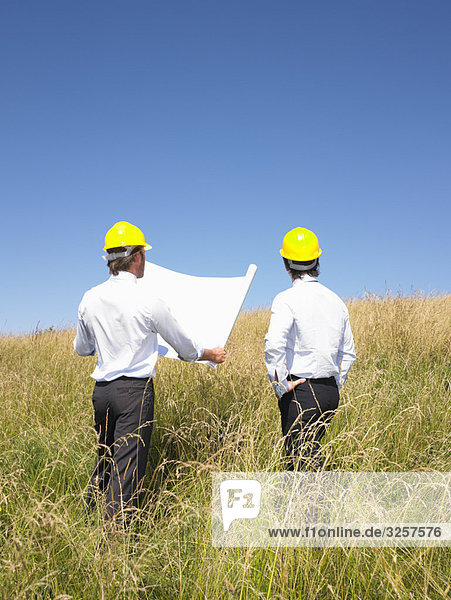contractors with blueprints in field