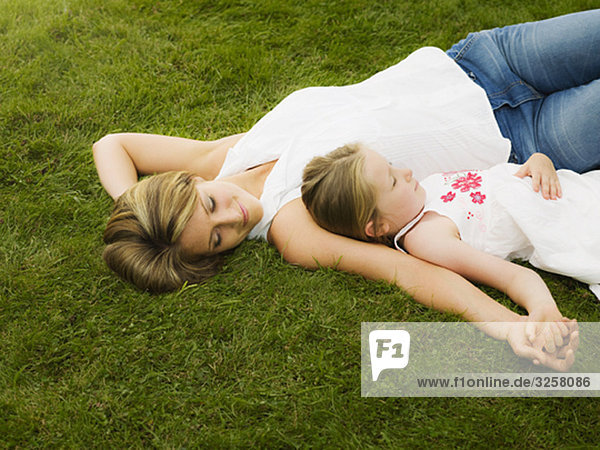 Mutter und Tochter liegen auf dem Rasen.