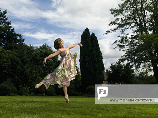 A young woman dancing in a garden