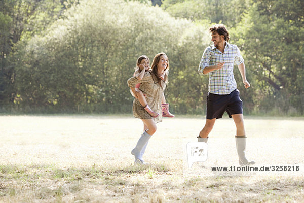 Family running together in country field