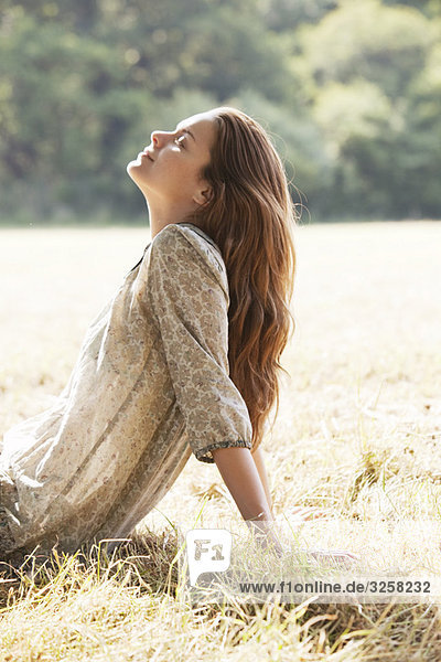 Woman lying back relaxing in field