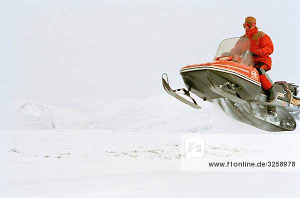 A man jumping with a snowmobile