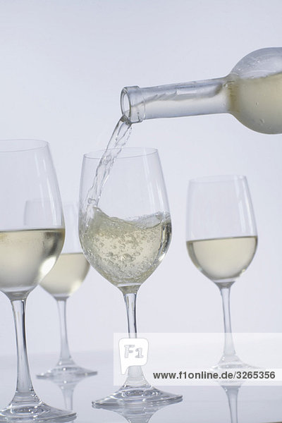 Gießen von Weißwein in Weingläser