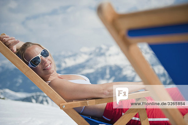 Österreich  Salzburger Land  Junge Frau im Liegestuhl liegend  lächelnd  Portrait