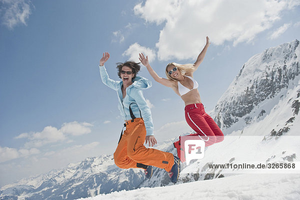 Österreich  Salzburger Land  Junges Paar springt in die Luft  lacht  Portrait