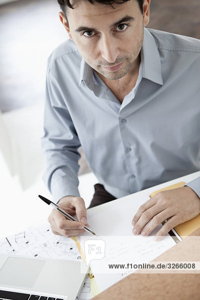 Geschäftsmann am Schreibtisch sitzend mit Kugelschreiber  Portrait  erhöhte Ansicht