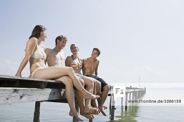 Germany  Bavaria  Ammersee  Young people sitting on jetty  smiling  portrait