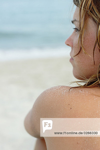 Italien  Sardinien  Junge Frau am Strand sitzend  Rückansicht  Nahaufnahme