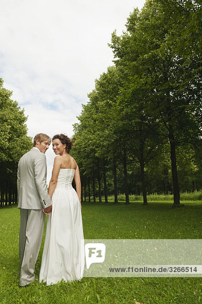 Germany  Bavaria  Bridal couple in park hand in hand  smiling  portrait