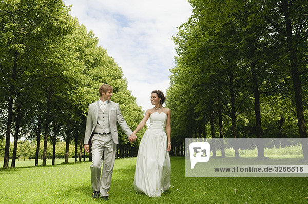 Deutschland,  Bayern,  Brautpaar im Park geht Hand in Hand,  lächelnd,  Portrait