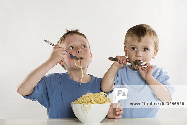 Two boys (6-7) (2-3) eating spaghetti  portrait