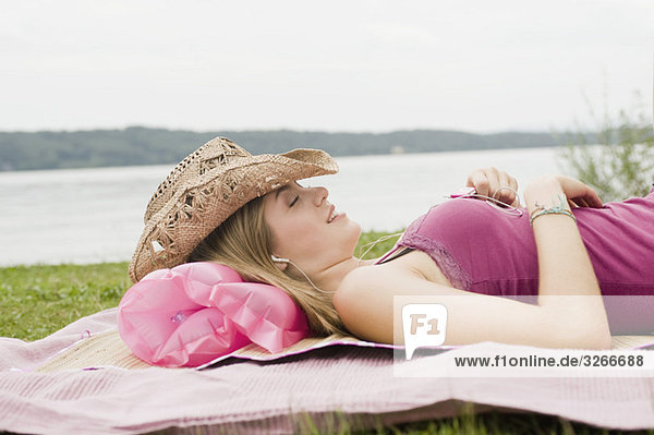 Starnberger See  Junge Frau auf Decke im Park liegend  mp3-Player hörend