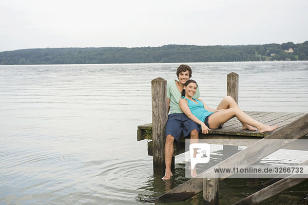 Germany  Bavaria  Starnberger See  Young couple sitting on jetty