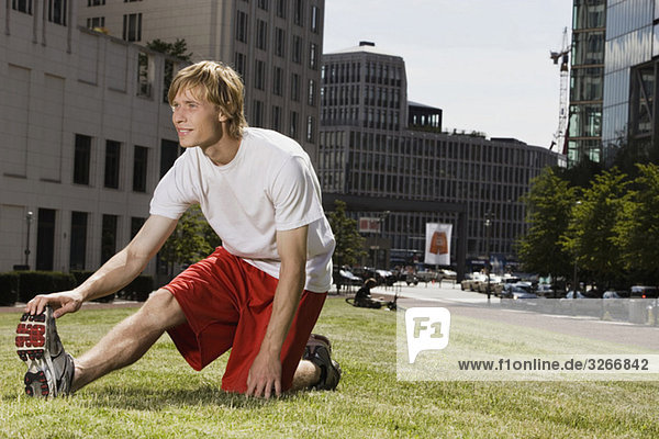 Young man stretching on lawn