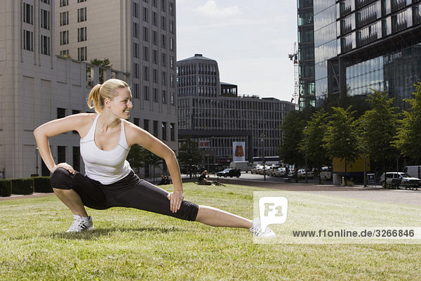Young woman doing stretching exercise on lawn