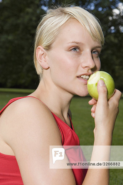 Junge Frau im Park beim Essen eines Apfels  Portrait