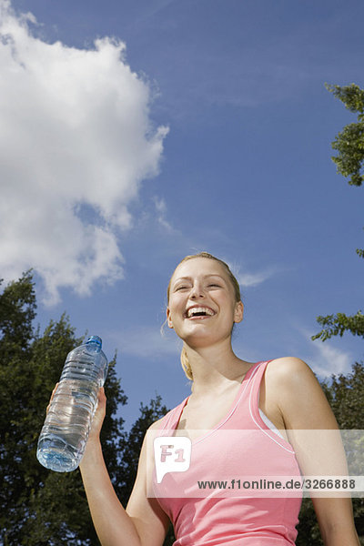 Junge Frau hält Wasserflasche  lacht  Portrait