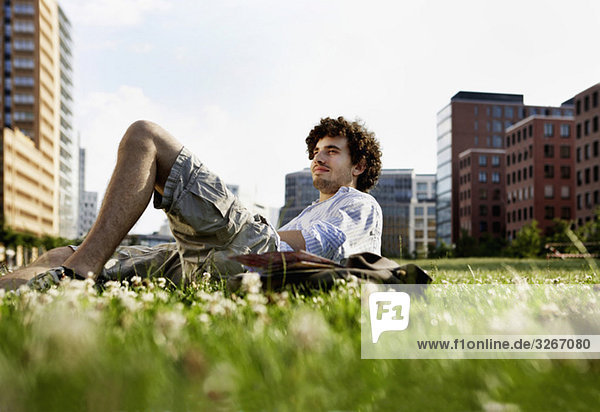 Man relaxing on lawn  in background high rise buildings