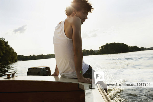 Junger Mann sitzt auf einem Motorboot.