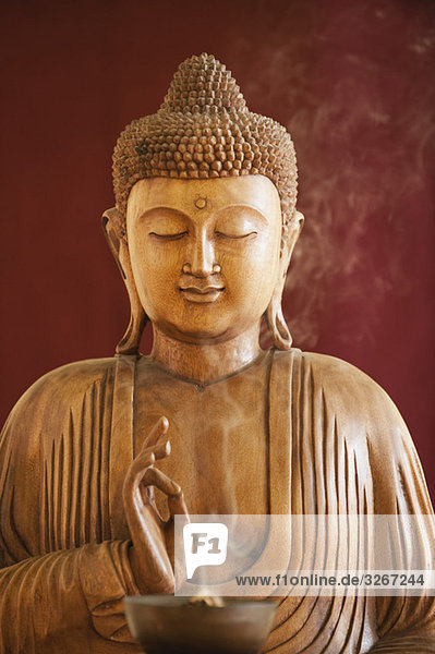 Buddha-Statue und eine Schale mit Räucherstäbchen